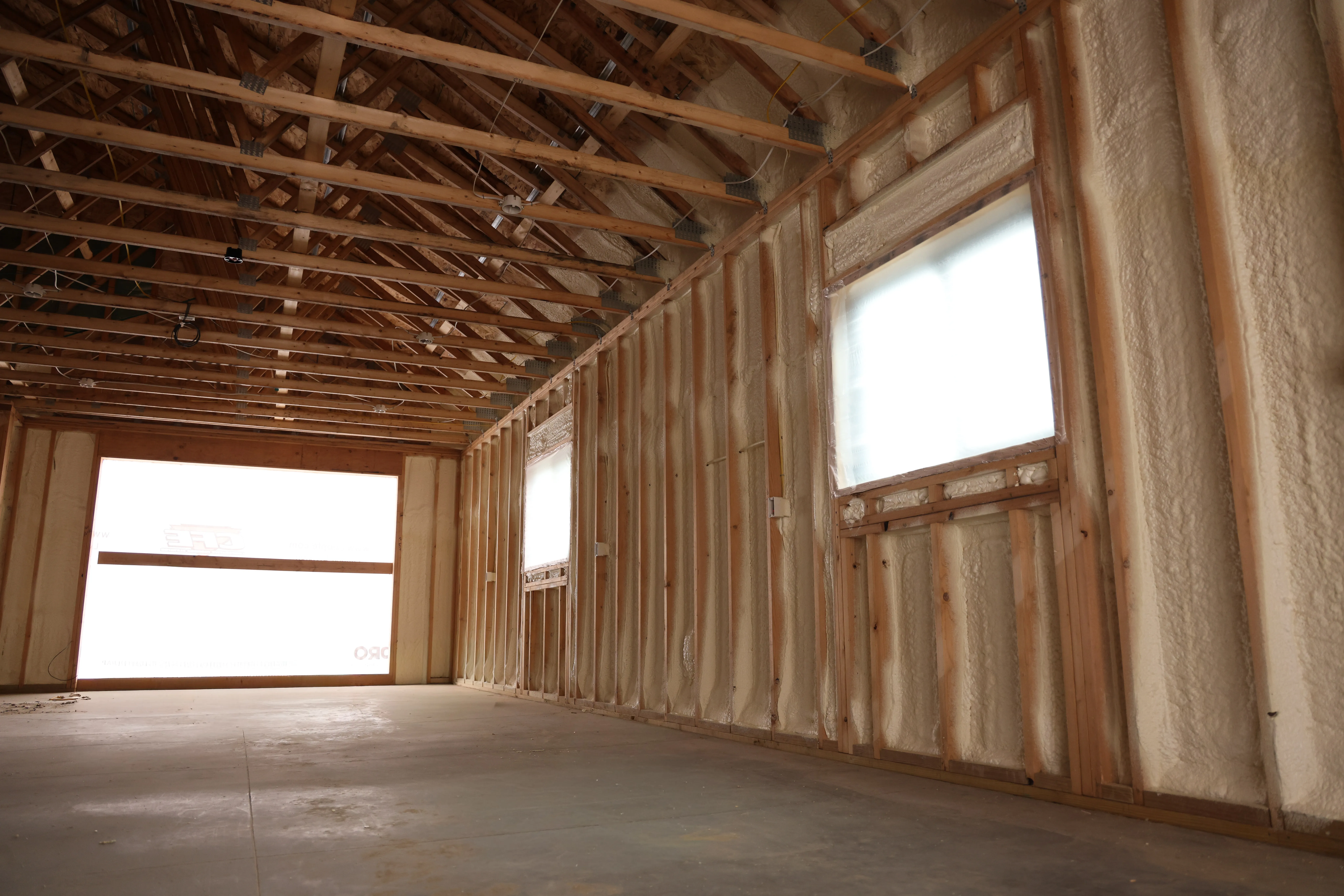 Pole barn interior with sprayed walls and a garage door opening